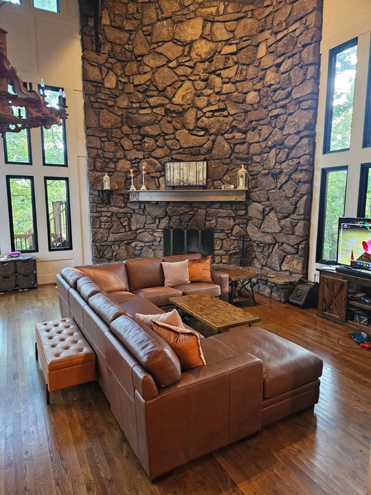 A customer's leather sectional in a great room with a stone fireplace wall